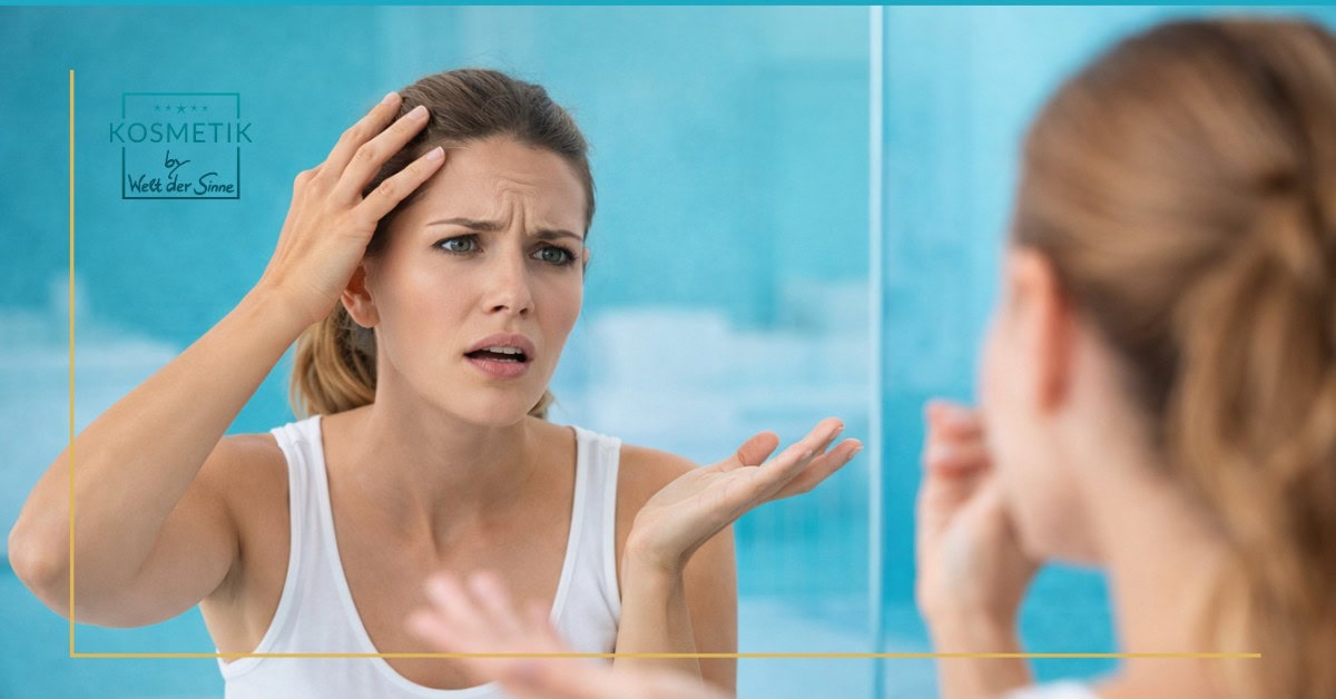 Verwirrte Frau steht vor dem Spiegel und betrachtet ihre Haut, die trotz gesunder Lebensweise müde und unrein wirkt